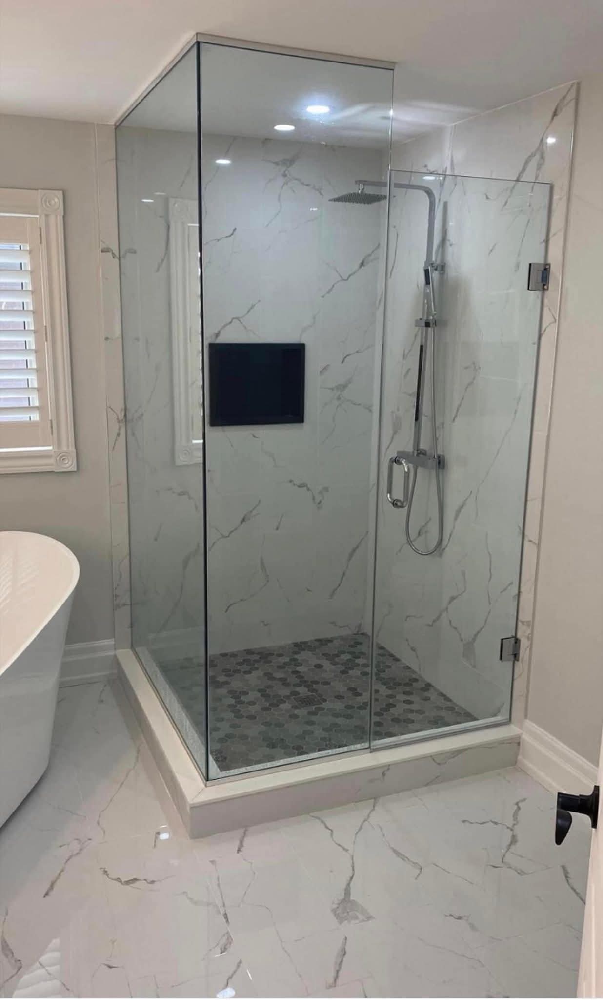 Bathroom renovation Oakville — corner walk-in shower with marble tile and hex penny floor by Cruzz Construction