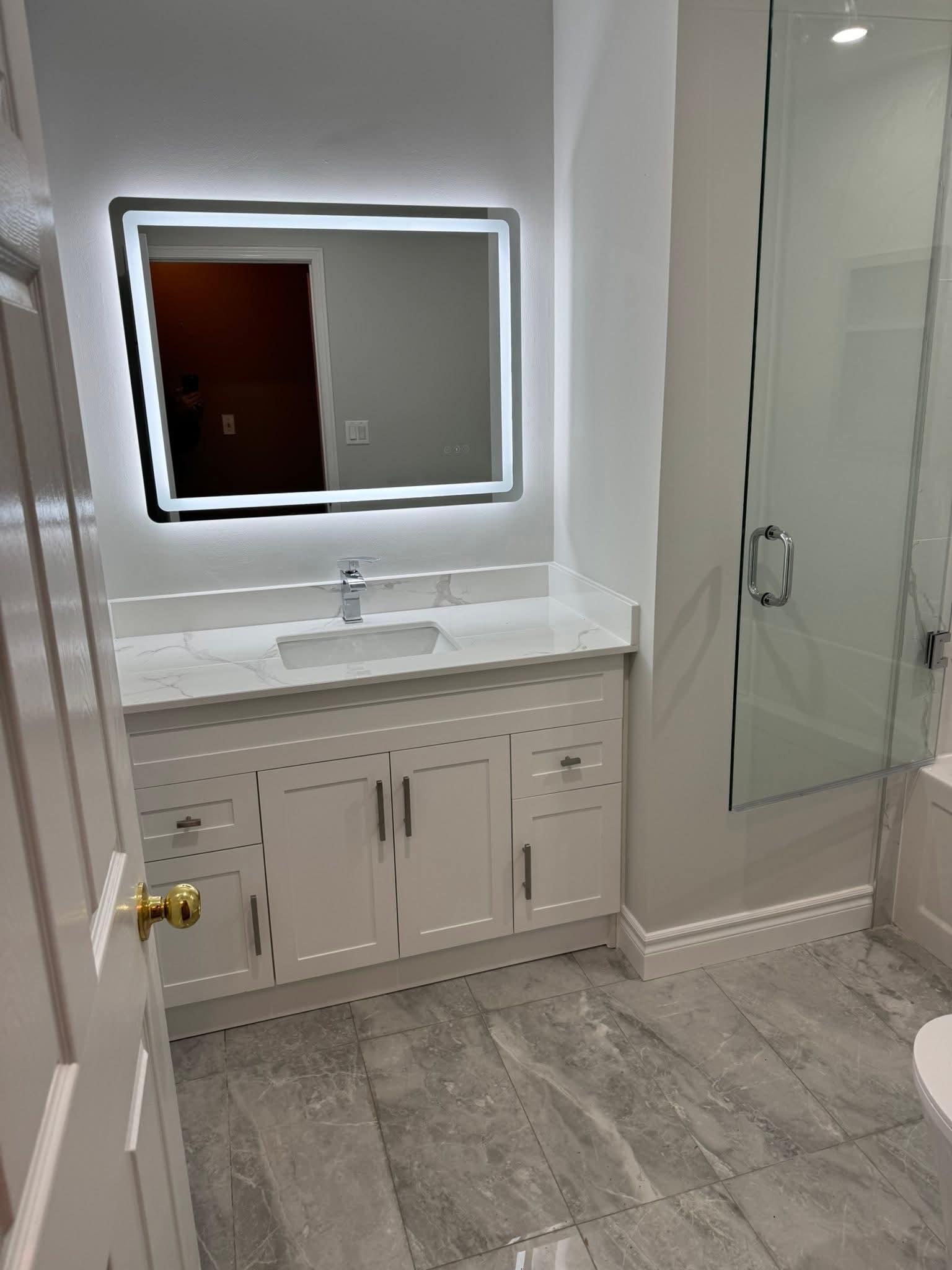 Bathroom renovation Oakville — double vanity with marble countertop and LED backlit mirror by Cruzz Construction