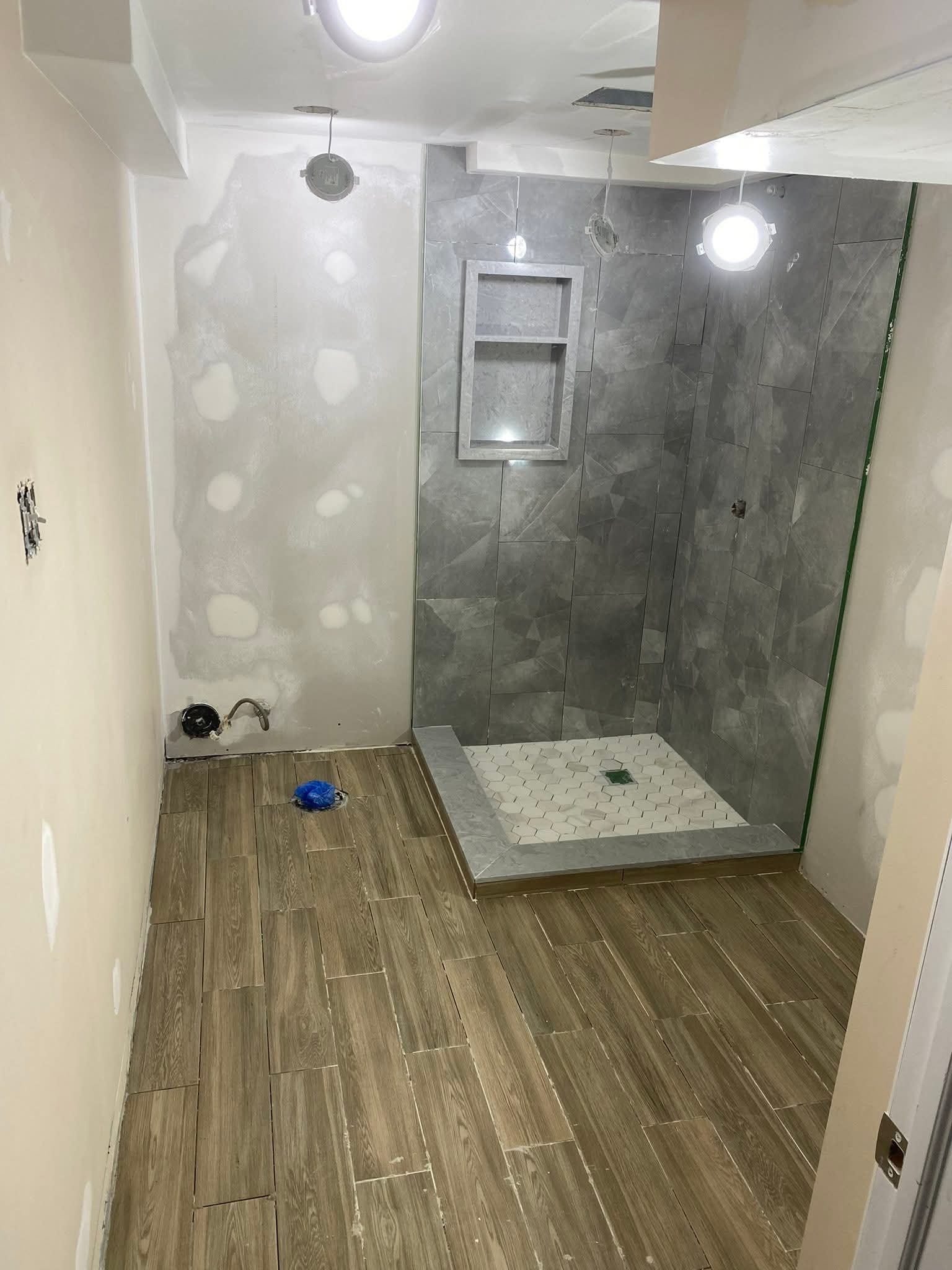 Oakville bathroom renovation in progress — custom shower niche tile work and wood-look porcelain floor by Cruzz Construction