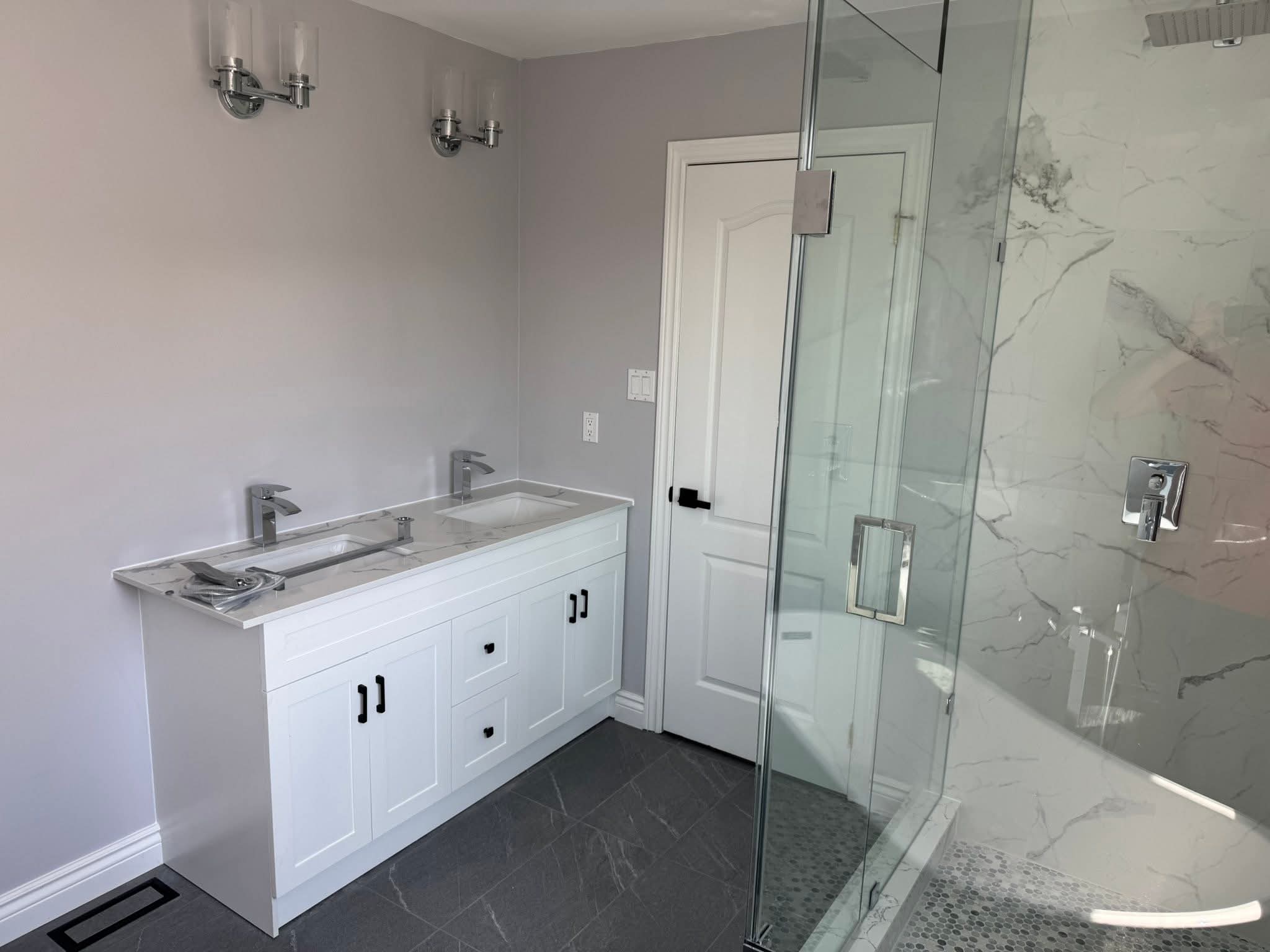 Luxury master ensuite renovation Oakville — double vanity with chrome sconces and walk-in shower by Cruzz Construction