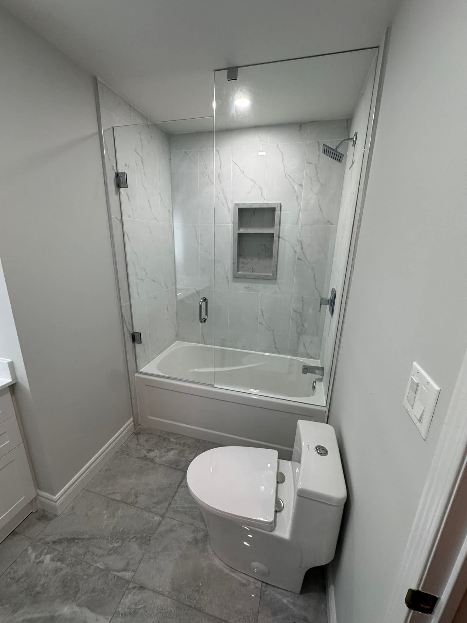 Oakville bathroom remodel — soaker tub with frameless glass enclosure and Calacatta marble tile by Cruzz Construction